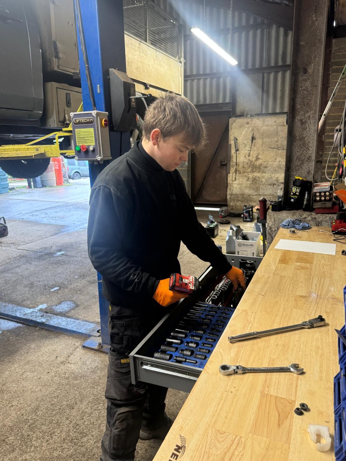 Southern VSR technician selecting sockets at the workshop bench beside a vehicle on the ramp